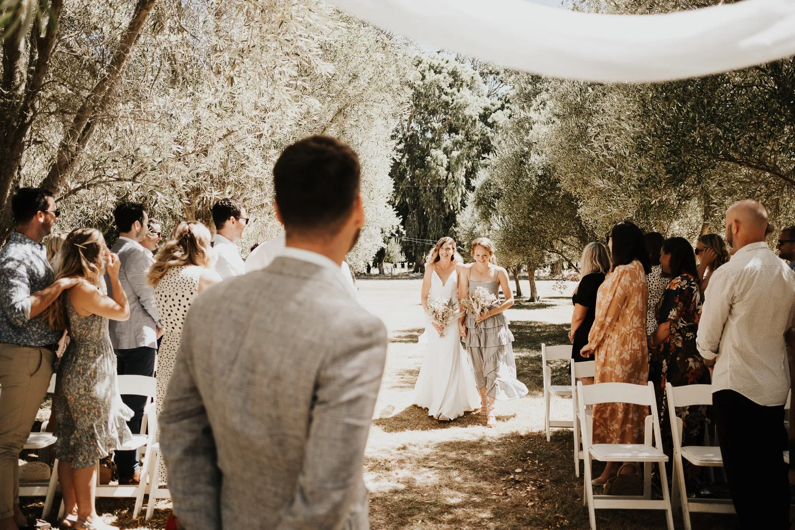 Aoife walking down the aisle toward Dan during their outdoor wedding ceremony.