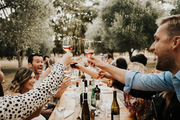 Wedding guests raising glasses for a toast at an outdoor reception.